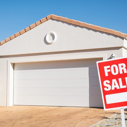 For sale sign outside a family house. Sale signboard outside home in lawn. Real estate board in front of new house for sale with copy space.